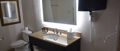 A bathroom with a sink, toilet, and a large mirror.