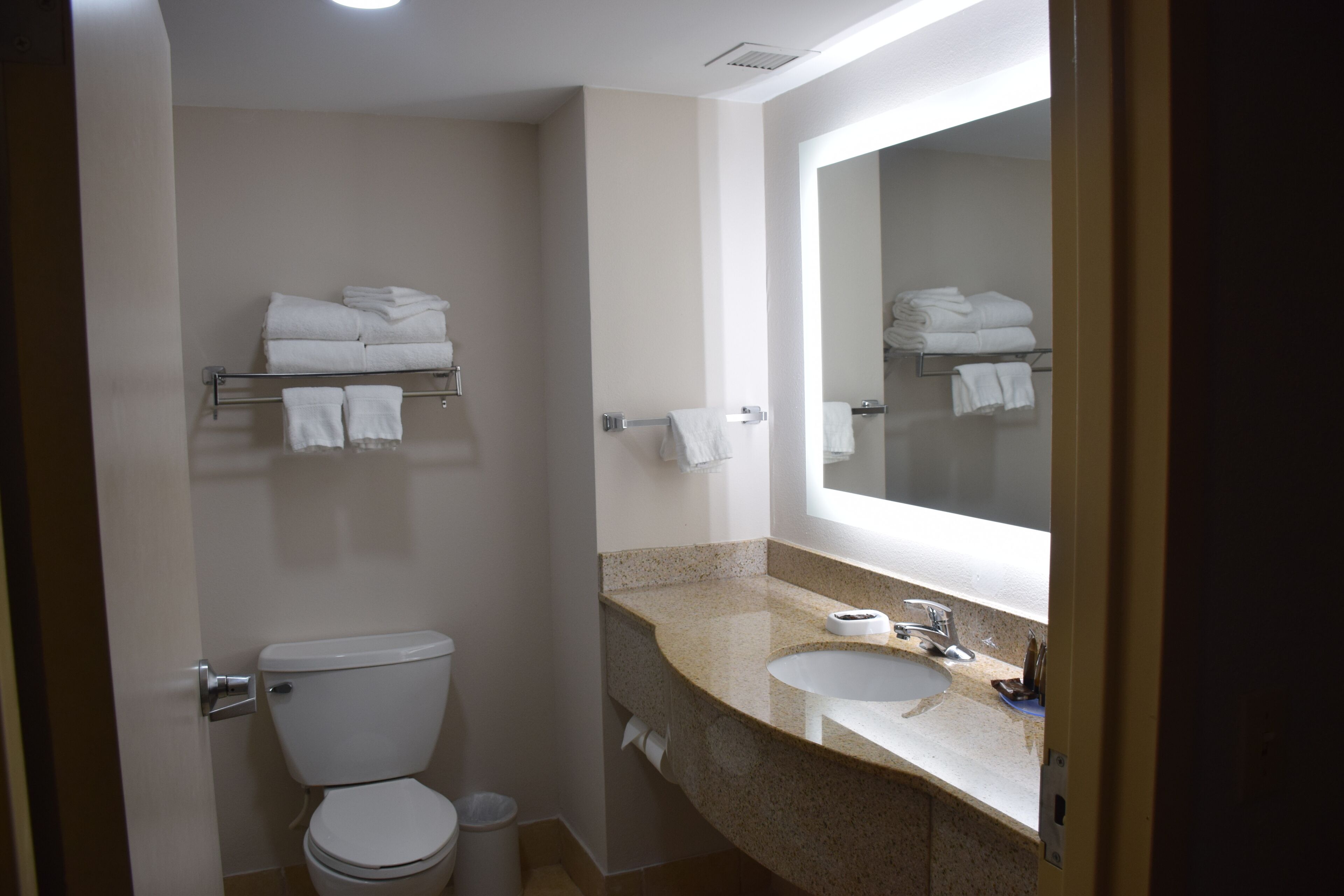 Un baño con inodoro, lavamanos y perchero para toallas.