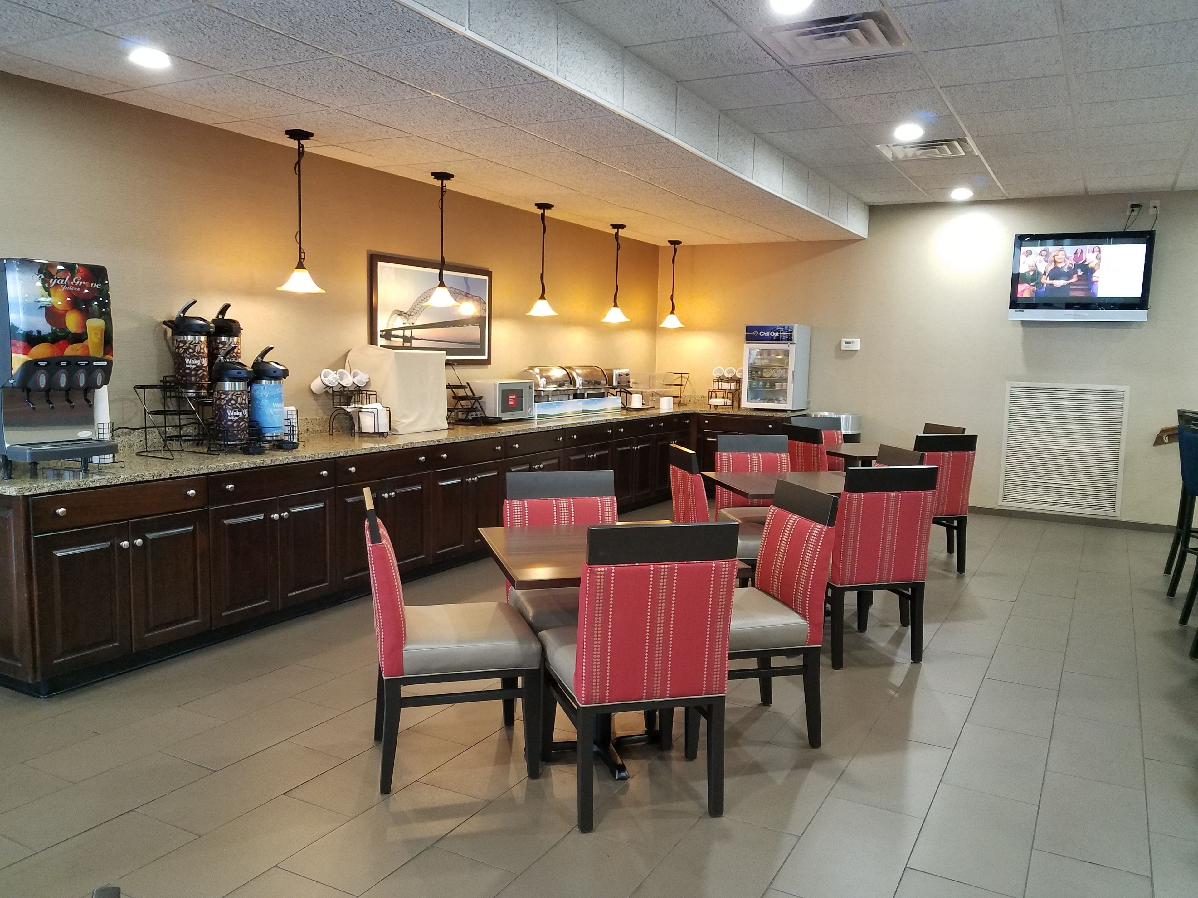 A restaurant with a counter, seating area, and a television screen.