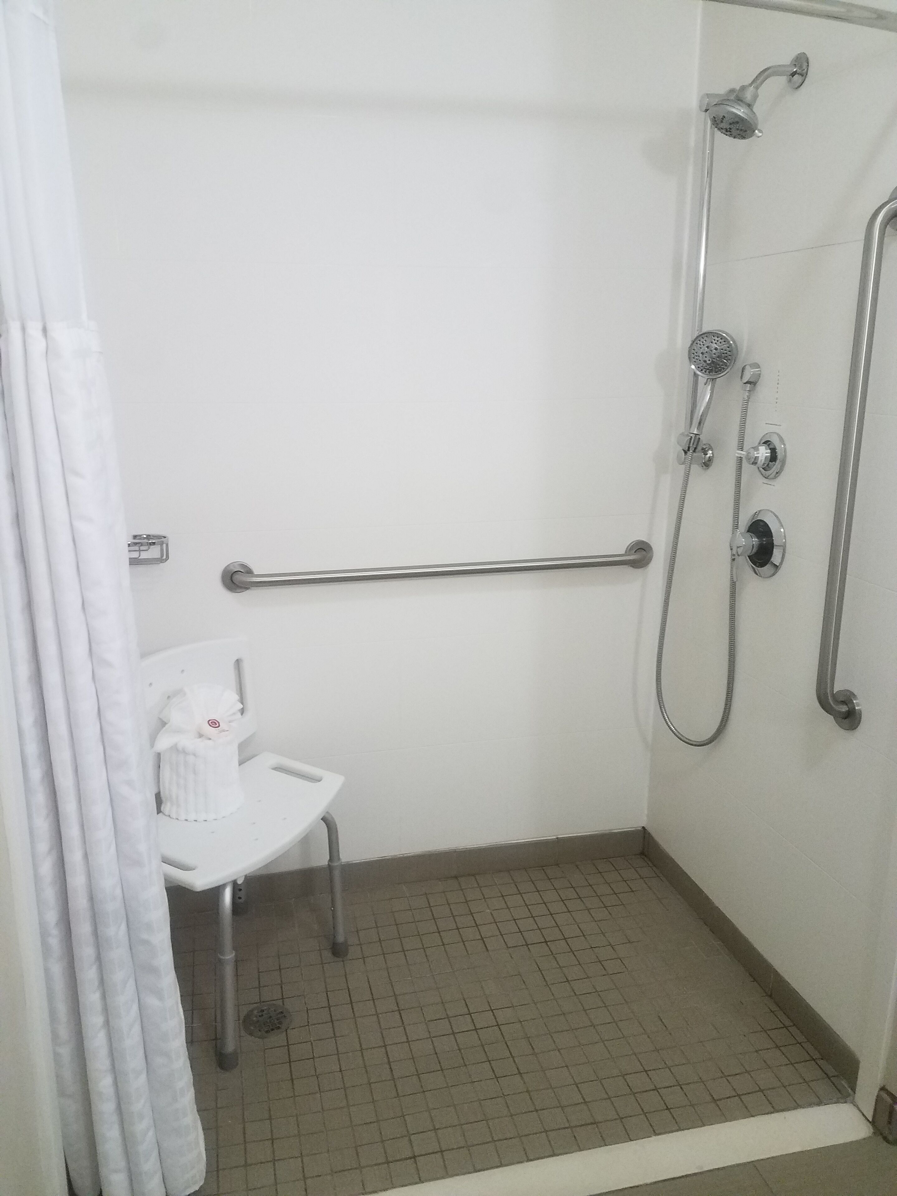 A shower area with a grab bar, a small white sink, and a showerhead.