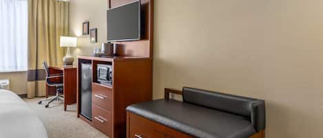 Une chambre d’hôtel comprenant un lit, un bureau avec un ordinateur, une télévision et un coin salon.