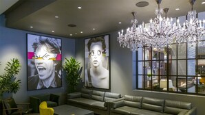 A modern lounge area with a grey sofa, yellow chairs, and a chandelier. - The Colonnade Hotel Back Bay (Boston)