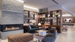 A modern living room with a fireplace, comfortable seating, and built-in bookshelves. - The Colonnade Hotel Back Bay (Boston)