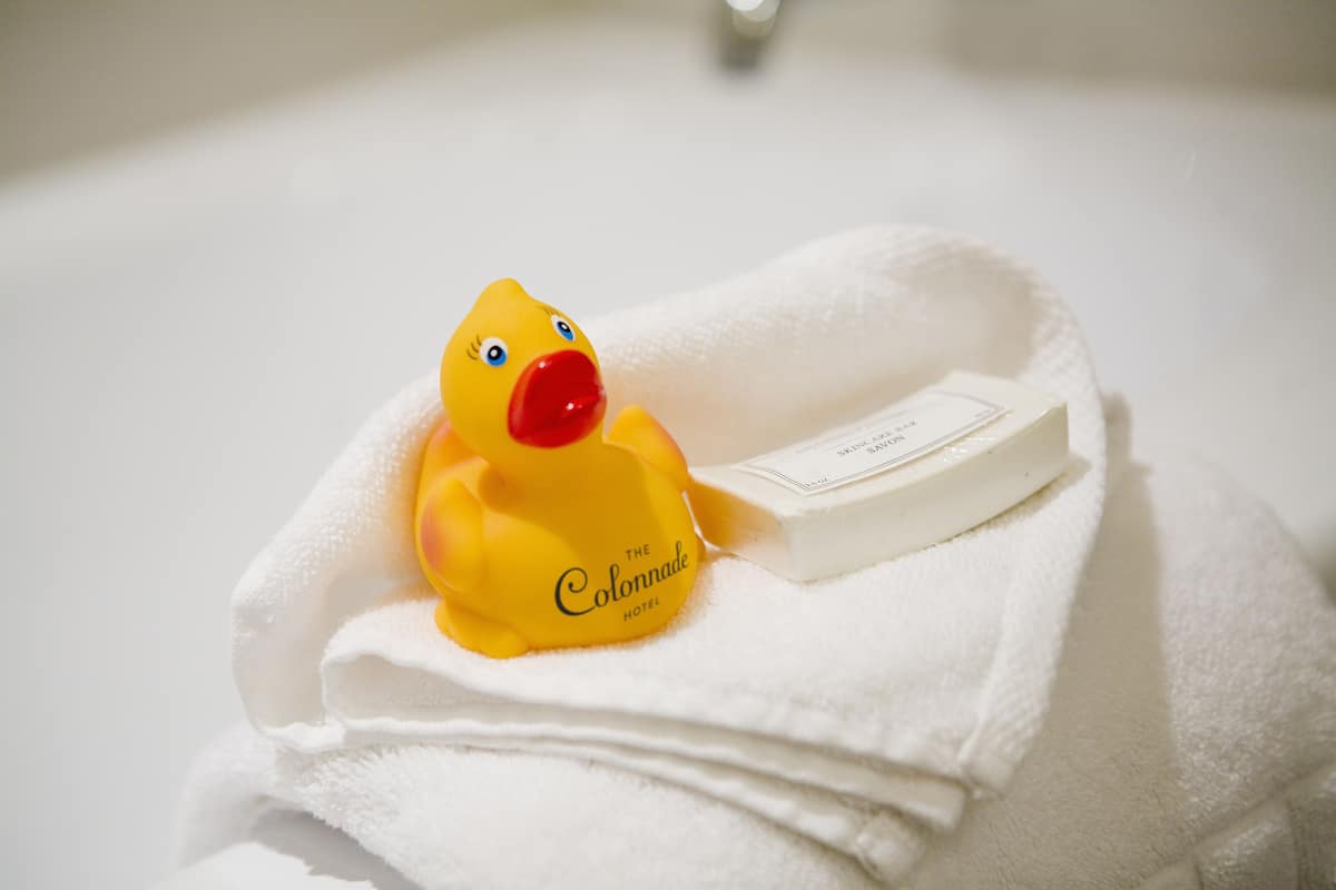 A yellow rubber duck with a red beak sitting on a folded white towel.