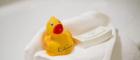 Un patito de goma amarillo con pico rojo sobre una toalla blanca doblada.