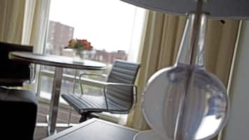 A hotel room with a round table, a chair, and a lamp.