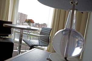 Una habitación de hotel con una mesa redonda, una silla y una lámpara.