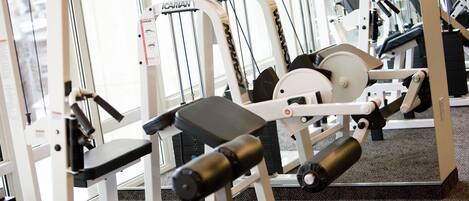 A gym with exercise machines, a mirror, and a carpeted floor.