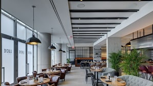 A modern restaurant with high ceilings, pendant lighting, and a mix of dining tables and seating areas. - The Colonnade Hotel Back Bay (Boston)