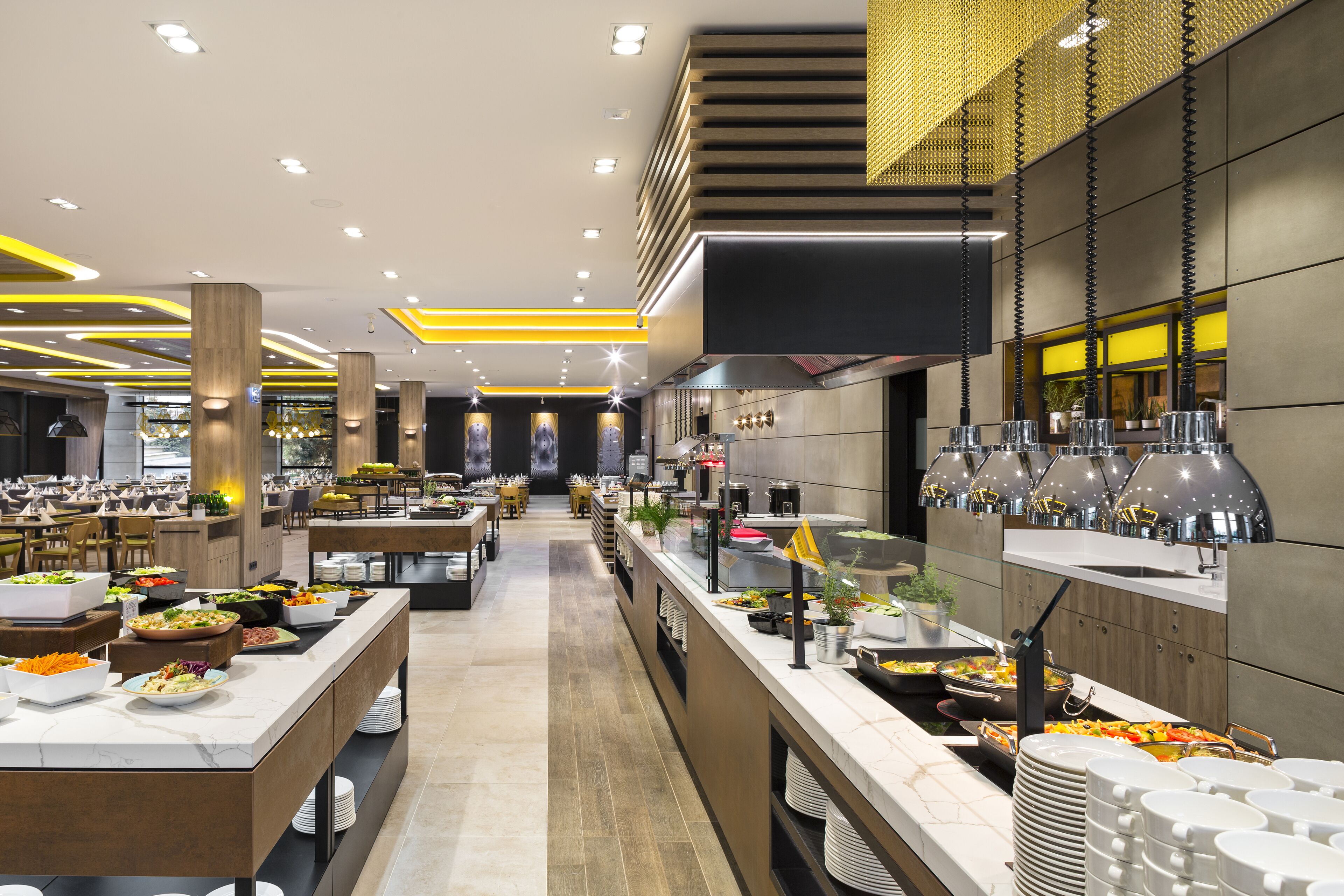 A modern buffet setup with multiple food stations, a central serving area, and a long counter with dishes.