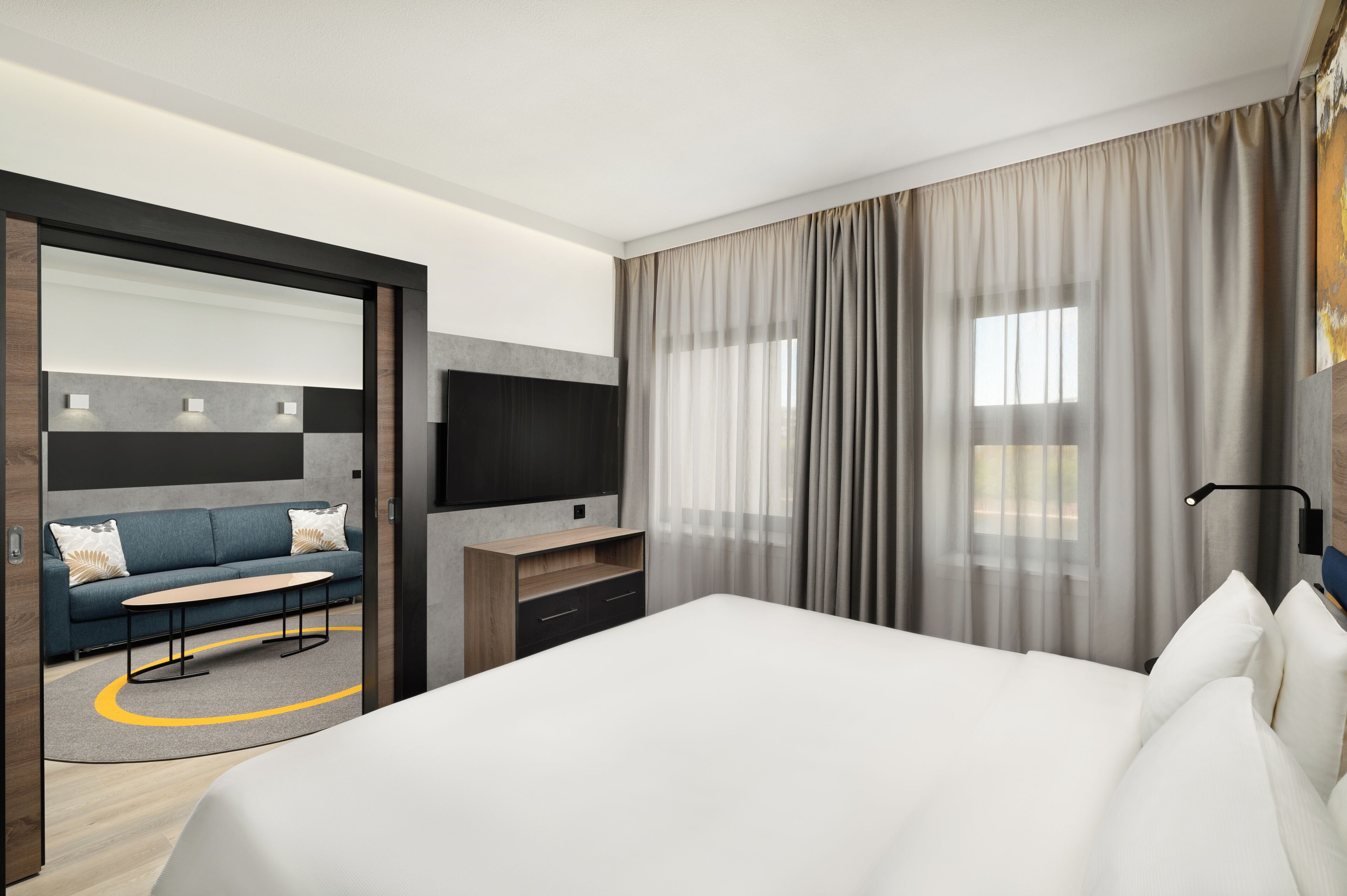 Una habitación de hotel moderna con una cama grande, un sofá, un televisor y un escritorio.