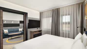Una habitación de hotel moderna con una cama grande, un sofá, un televisor y un escritorio.