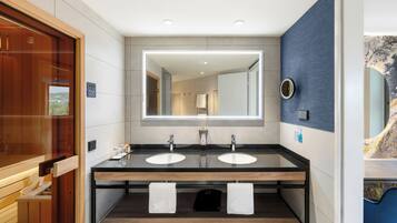 A modern bathroom with two sinks, a large mirror, and a wooden vanity.