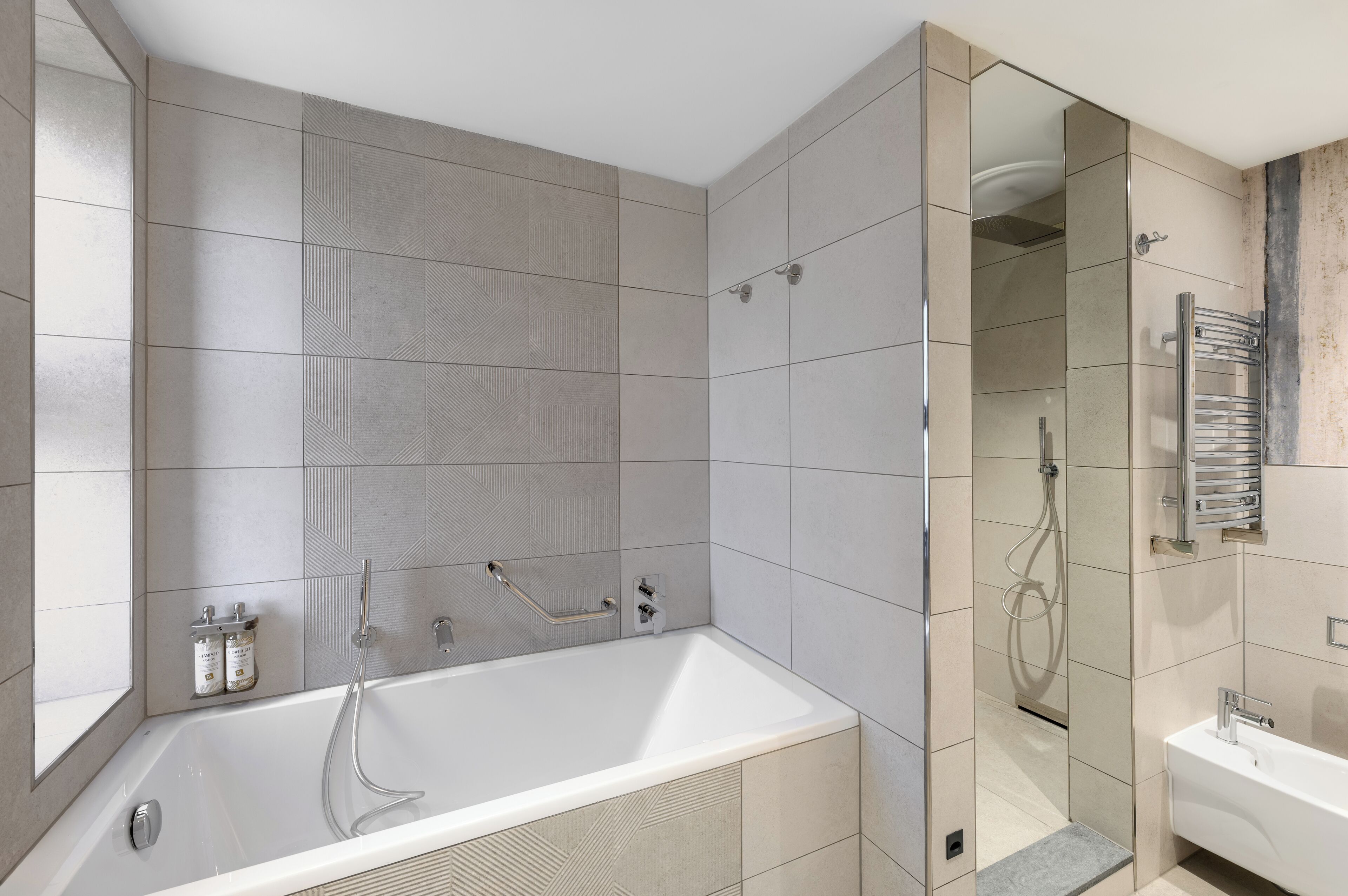 Un baño moderno con una bañera independiente, ducha con mampara de vidrio y zona de lavamanos separada.