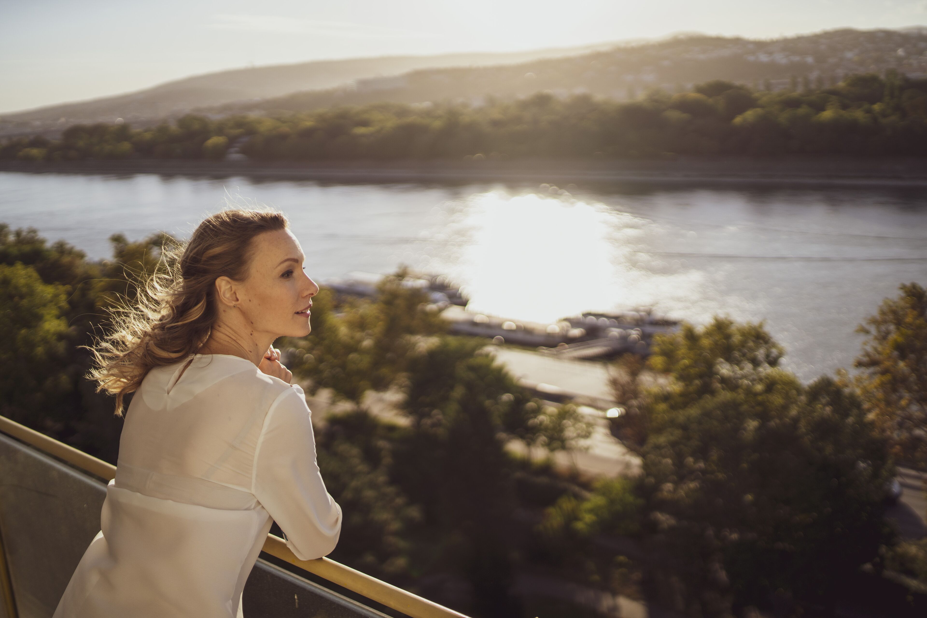 A person overlooking a river with a bridge in the distance.