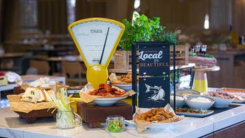 Un buffet con diversi cibi, una bilancia e un cartello con la scritta 'Local is Beautiful'.