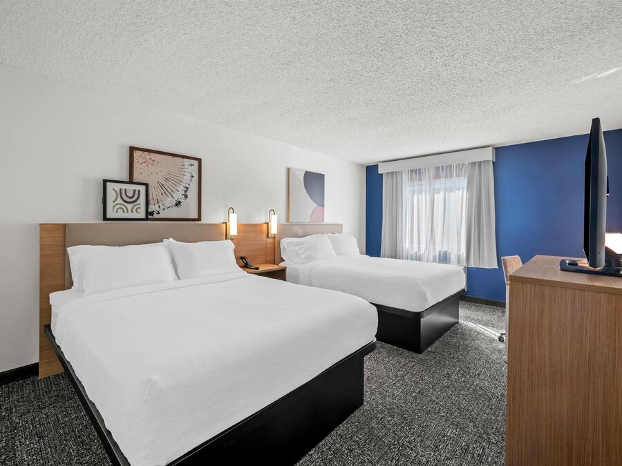 Een hotelkamer met twee bedden, een bureau, een stoel en een televisie.