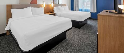 A hotel room with two beds, a flat-screen TV, a desk, and a large window with curtains.
