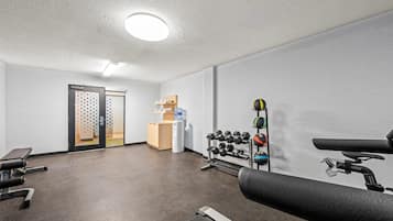 Ett gym med träningsutrustning, en vattenautomat och ett litet träskåp.