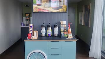 A beverage station with a variety of drinks and a TV screen displaying a food advertisement.