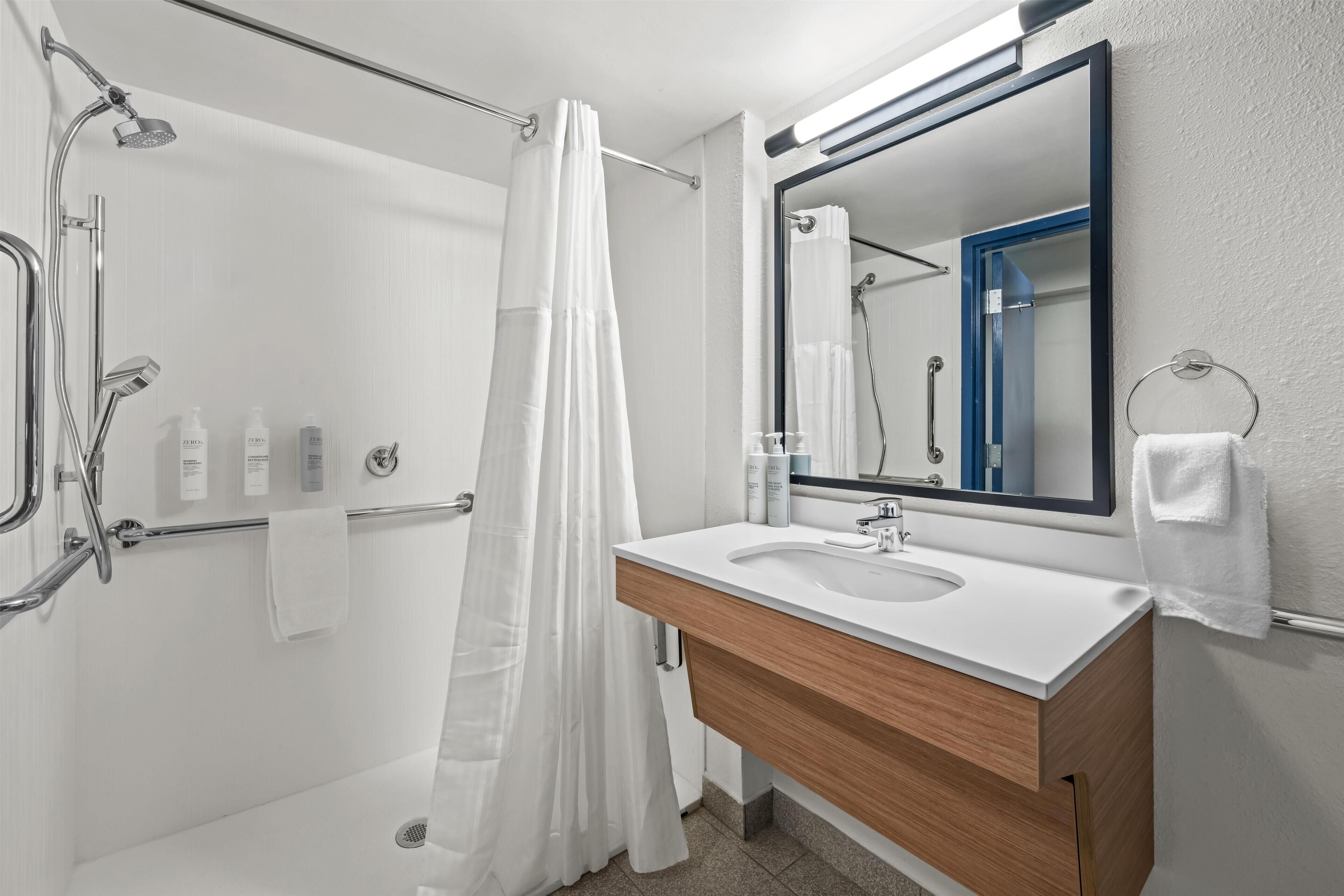 A modern bathroom with a shower, a sink, and a mirror.