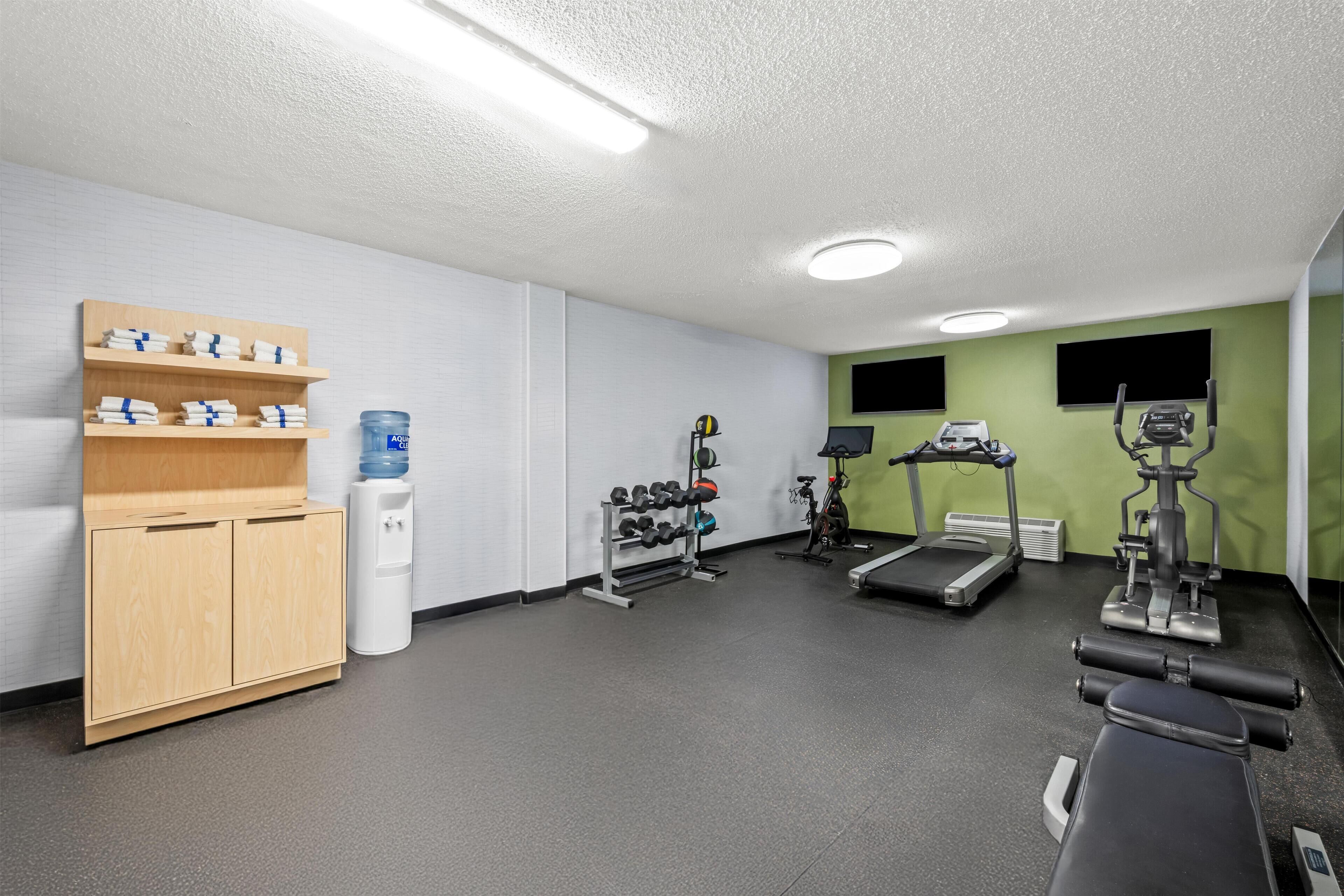 A gym with exercise equipment, a water dispenser, and a towel rack.