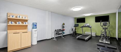 A gym with exercise equipment, a water dispenser, and a towel rack.