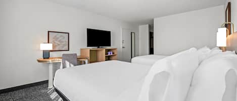 Una habitación de hotel con una cama grande, un escritorio con lámpara, un televisor y un armario.