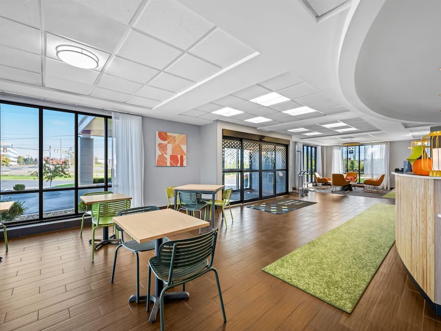 A modern hotel lobby with large windows, wooden flooring, and a reception desk.