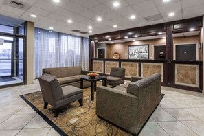 A hotel lobby with a seating area, a reception desk, and a large window with curtains. - Super 8 by Wyndham Atoka (Atoka)