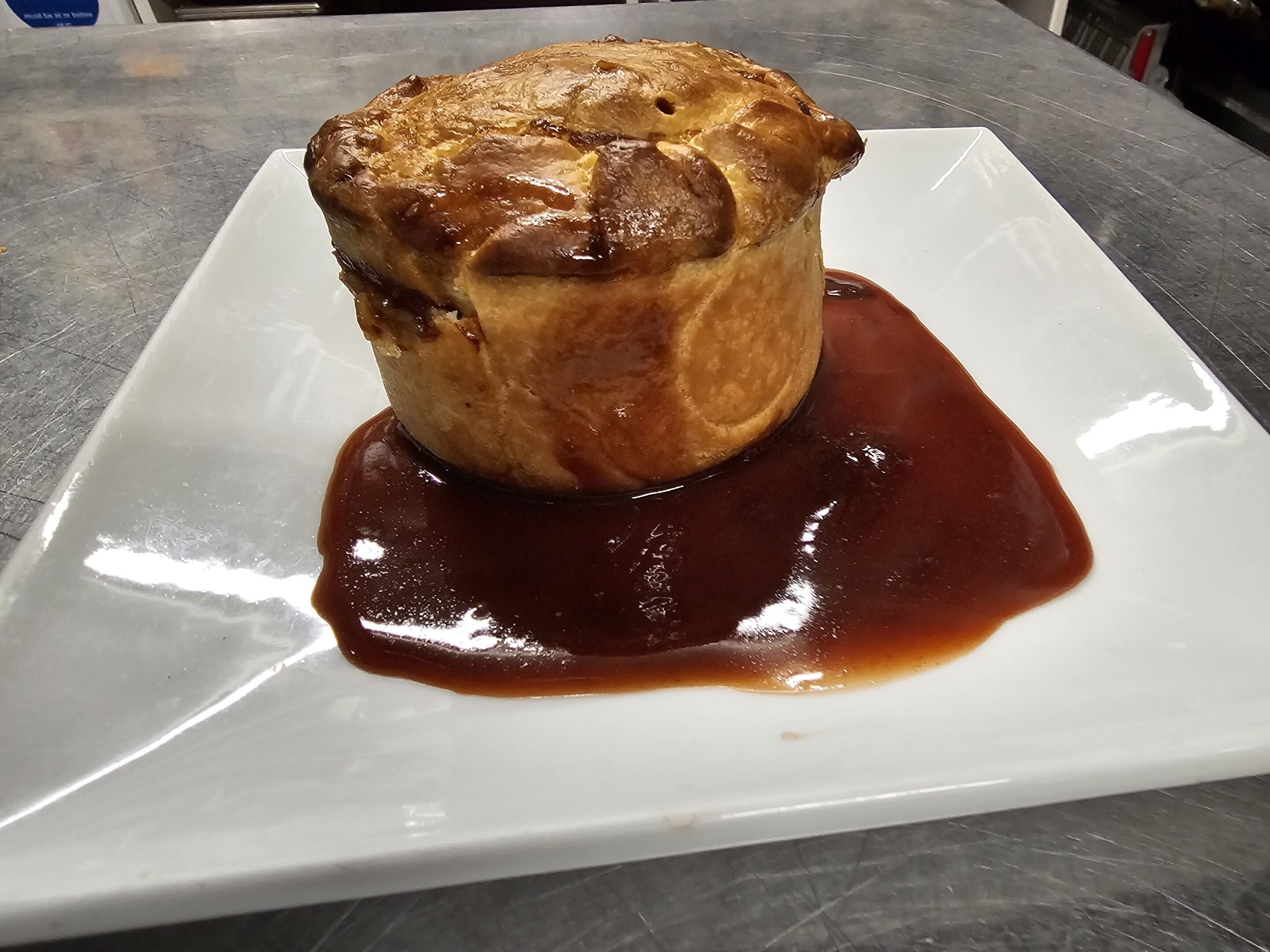 Un dessert servi dans une assiette blanche, nappé d’une sauce foncée.