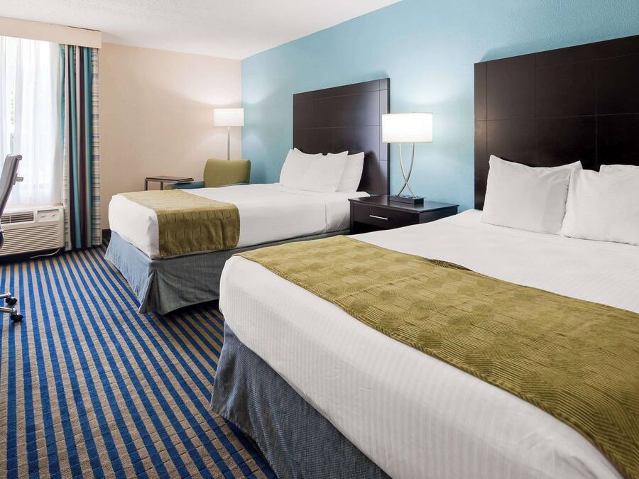 A hotel room with two beds, a desk, and a chair.