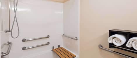 A bathroom with a bathtub, a shower, and a towel rack with towels.