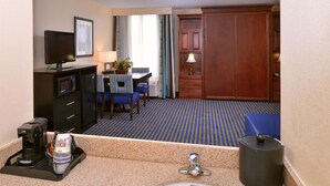 A hotel room with a kitchenette, a dining area, a large wooden wardrobe, and a bathroom with a sink and mirror. - Best Western Leesburg Hotel & Conference Center (Leesburg)