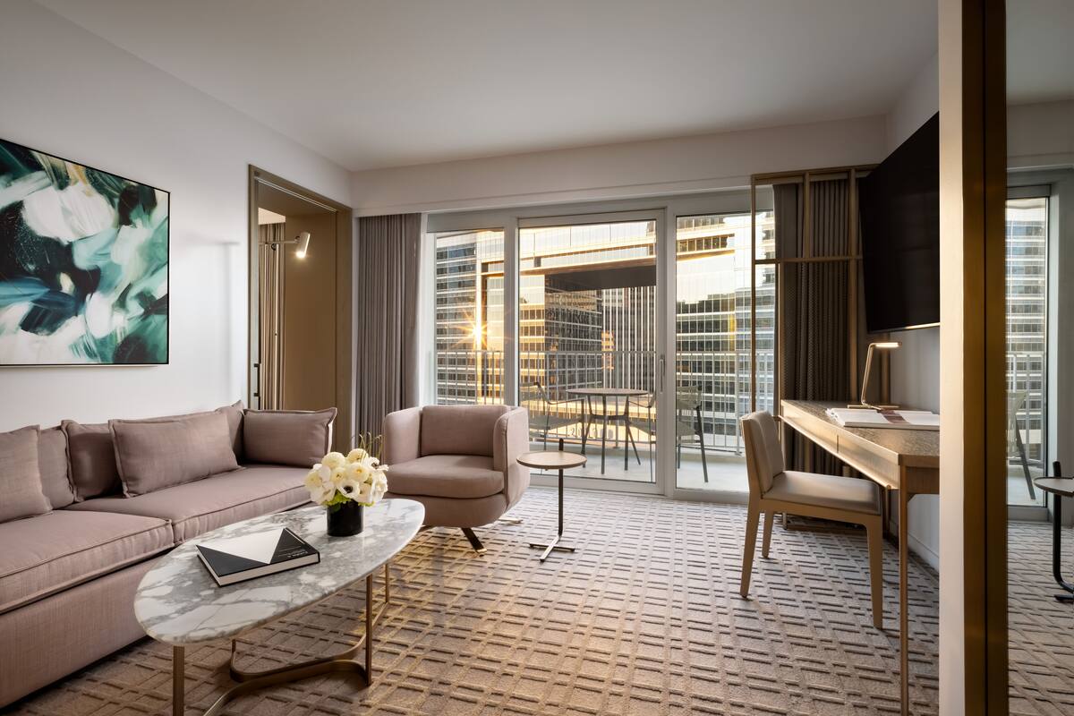 Ein modernes Hotelzimmer mit einer Couch, einem Sessel, einem Couchtisch und einem Schreibtisch.