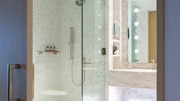 A modern bathroom with a glass-enclosed shower, a vanity with a mirror, and a marble floor.