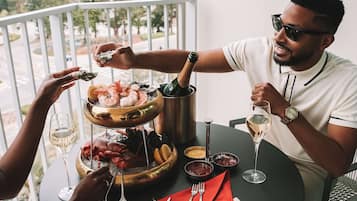 A balcony with a dining table set for two, featuring a seafood platter, wine glasses, and a bottle of champagne.