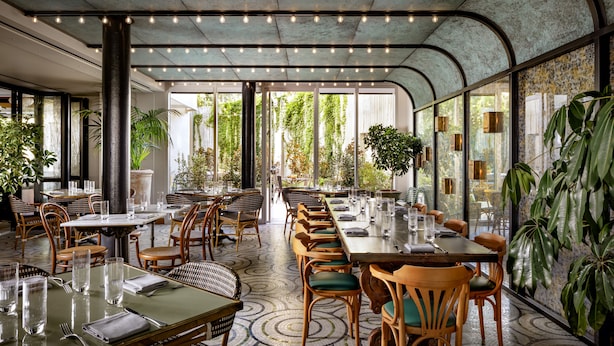 A spacious restaurant with high ceilings, large windows, and a variety of seating arrangements including tables and chairs.
