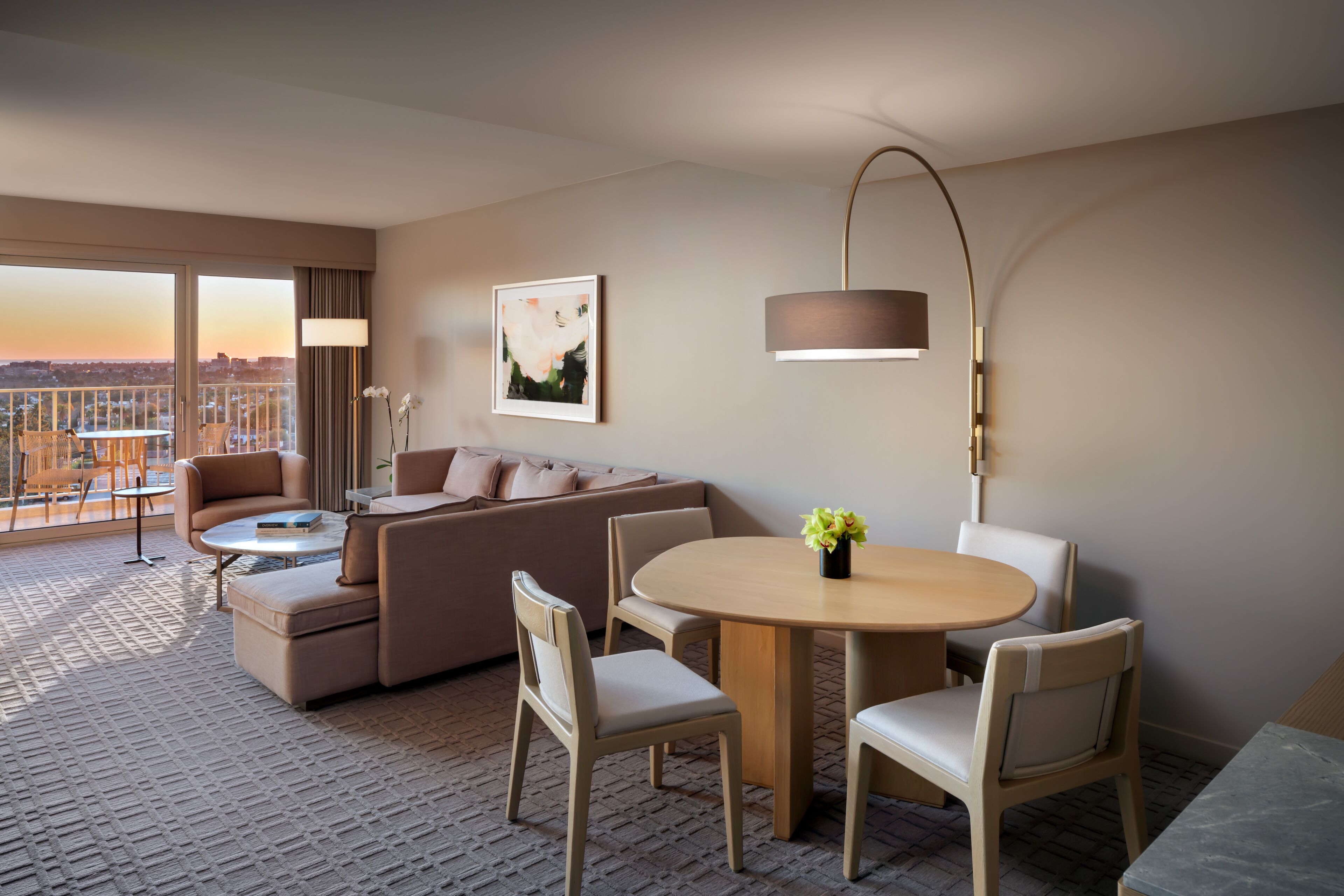 Une chambre d’hôtel avec un canapé, des fauteuils, une table ronde et une vue sur le paysage urbain.