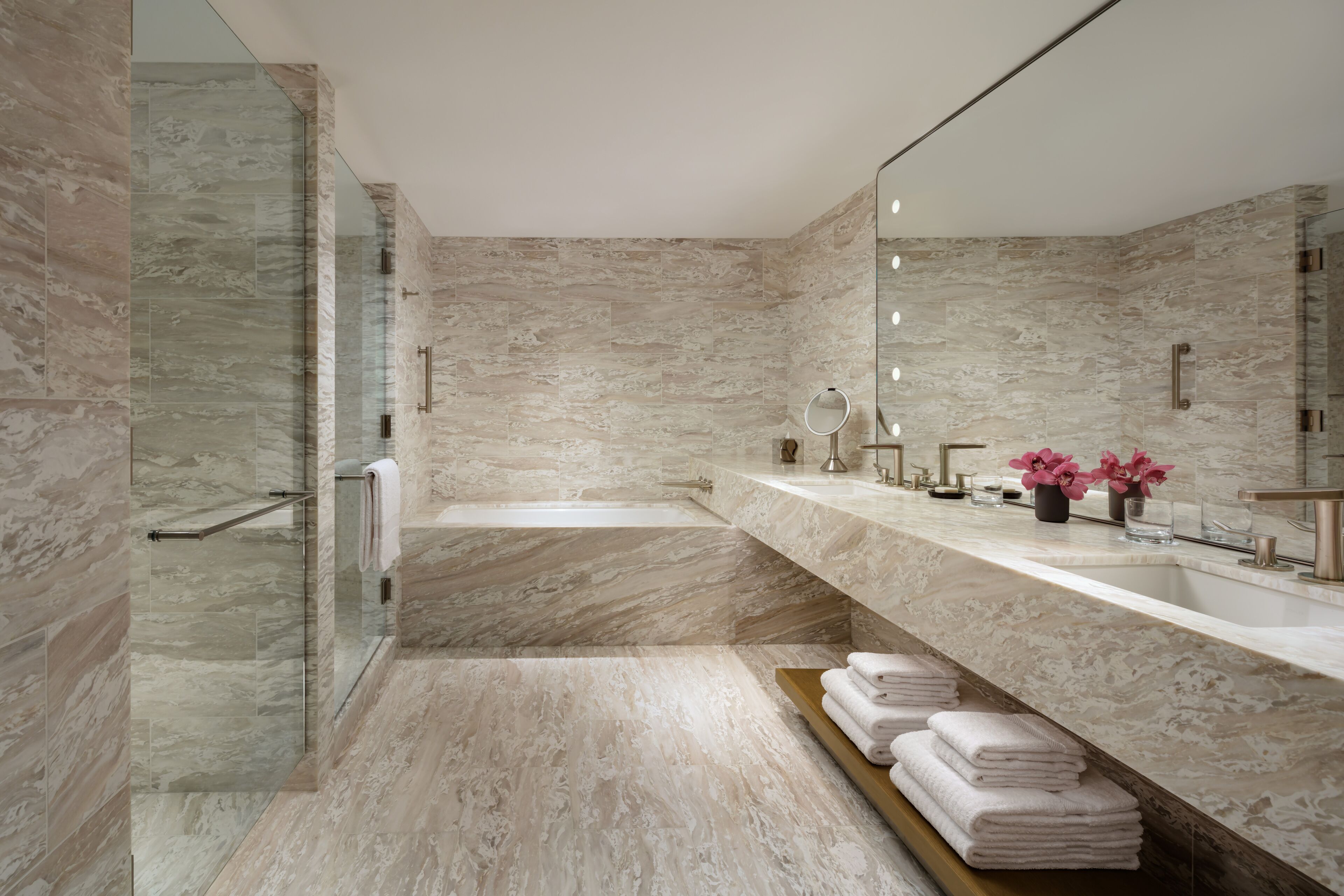 A modern bathroom with a large mirror, a bathtub, and a vanity with a sink and countertop.
