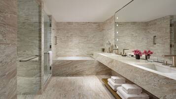 A modern bathroom with a large mirror, a bathtub, and a vanity with a sink and countertop.
