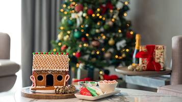 A gingerbread house on a table with a Christmas tree in the background.