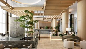 A spacious lobby with a central island, seating areas, and a modern staircase.