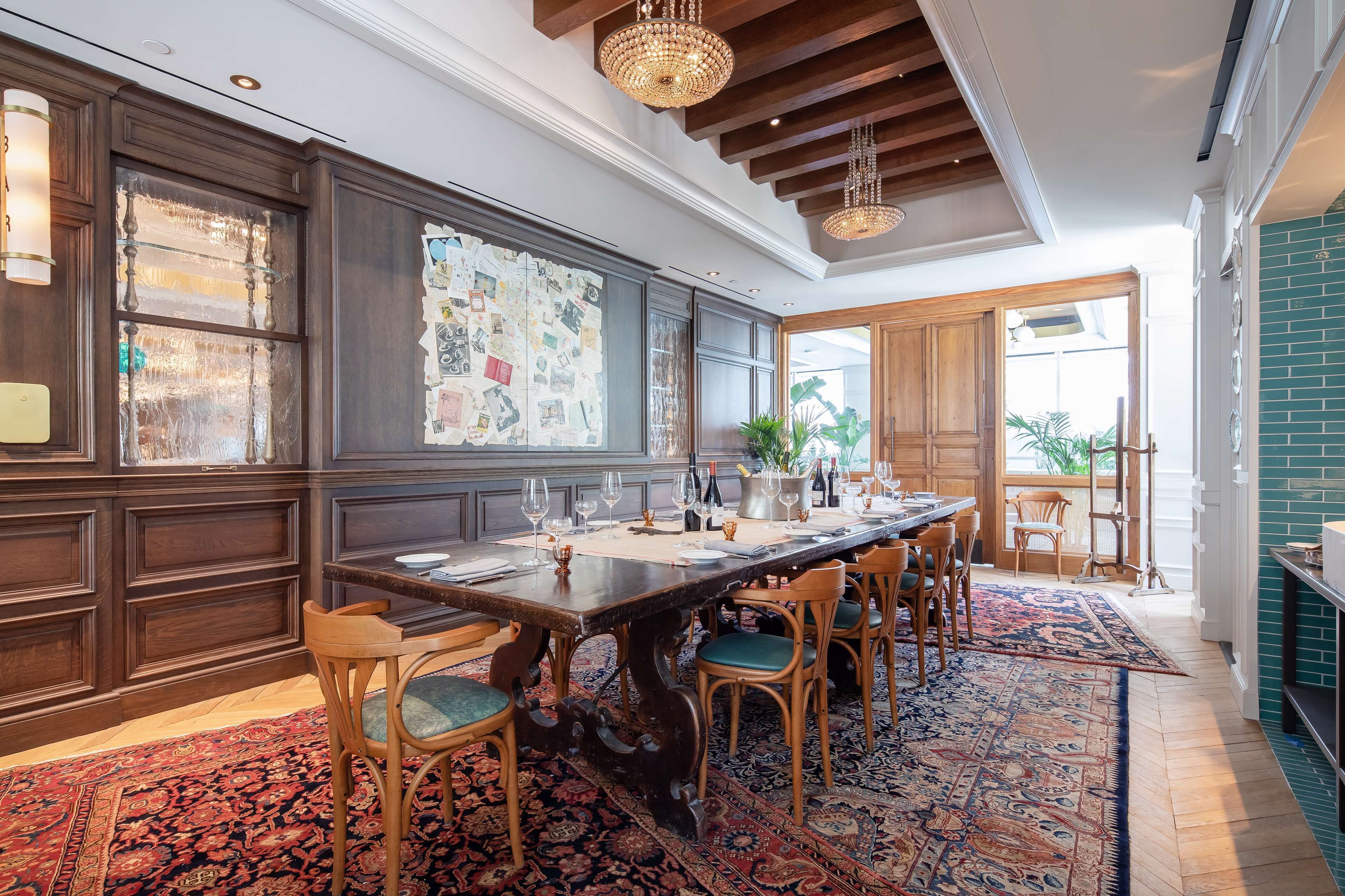 Un comedor con una mesa de madera larga, varias sillas y un tapete estampado.