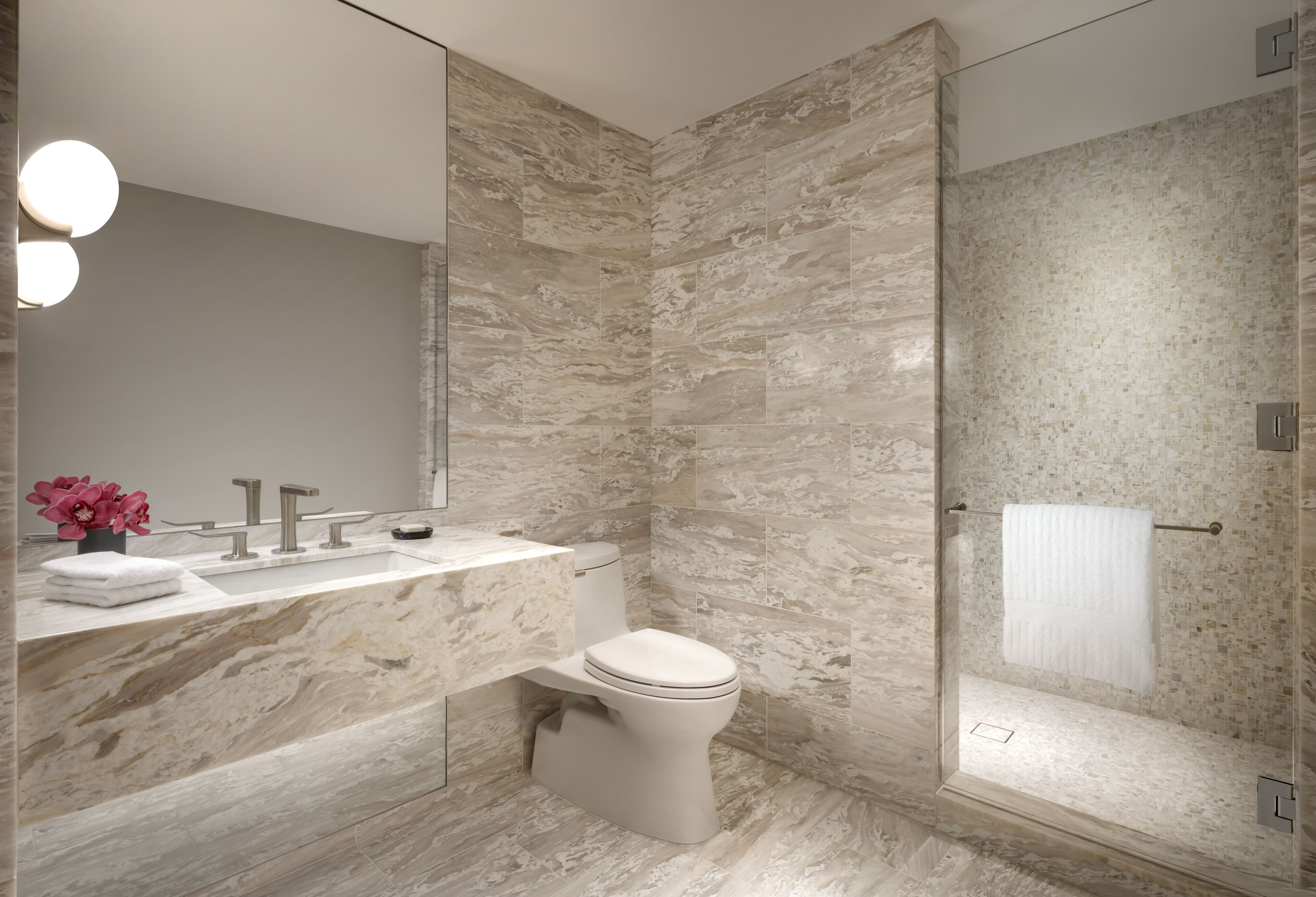 Ein modernes Badezimmer mit Marmorwaschbecken, Toilette und Dusche.