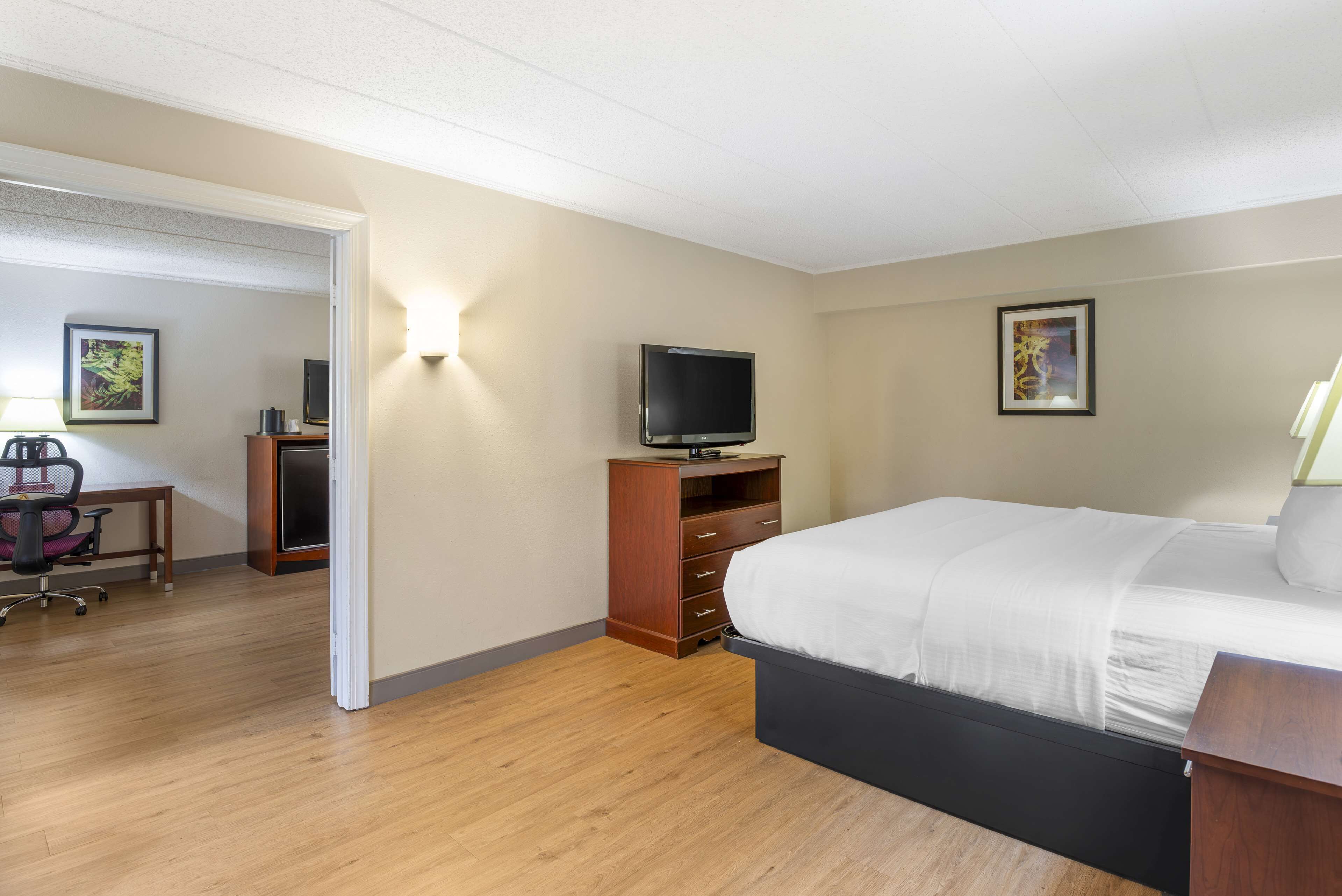 A hotel room with a bed, a desk with a computer, a TV, and a chair.