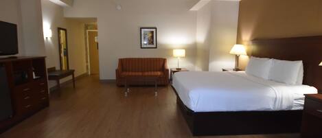 A hotel room with a bed, a sofa, a TV, and a desk.