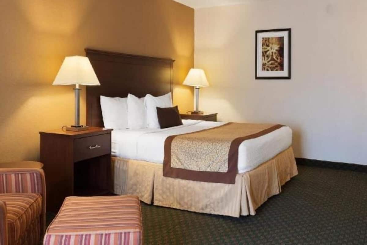 A hotel room with a bed, two bedside tables with lamps, a chair, and a small table.