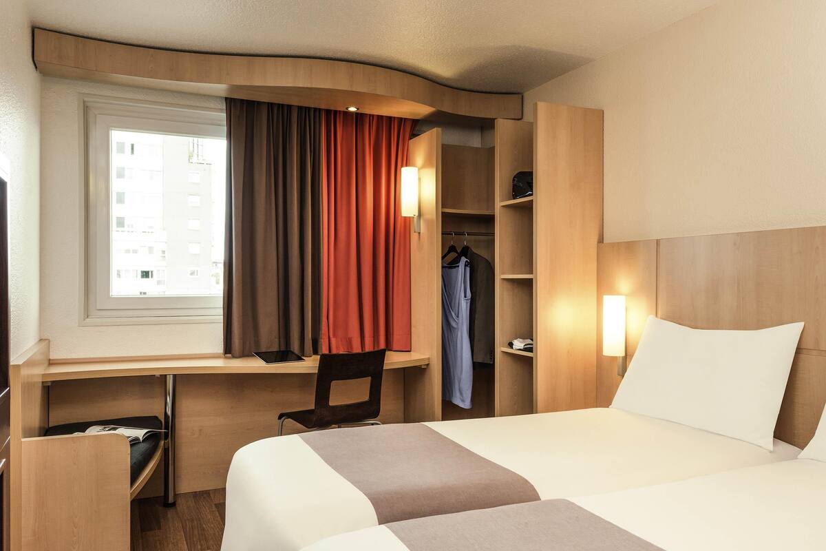 Une chambre d’hôtel équipée d’un lit, d’un bureau, d’une chaise et d’une armoire.