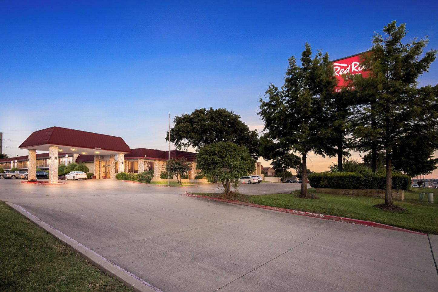 A Red Roof Inn with a red roof, stone facade, and a parking lot.